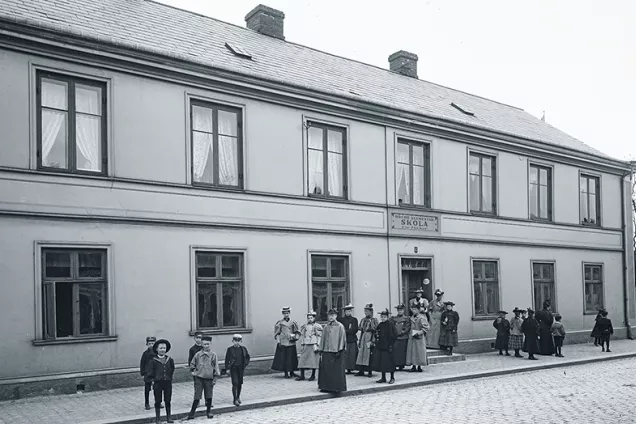 Tvåvåningshus från 1800-talet med. människor framför. Foto. 