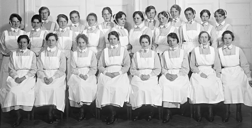 Gruppbild med kvinnor i äldre sjuksköterskeuniform. Foto.